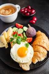 fried egg breakfast croissant, vegetables salad tomato, cucumber ready to eat meal snack on the table copy space food background rustic keto or paleo diet veggie vegetarian food 