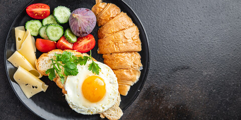 fried egg breakfast croissant, vegetables salad tomato, cucumber ready to eat meal snack on the table copy space food background rustic keto or paleo diet veggie vegetarian food 