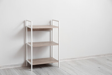 Stylish shelf unit near light wall
