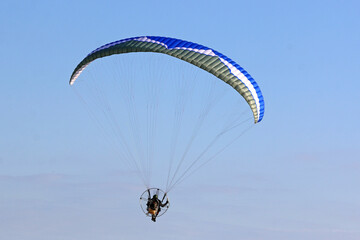 	
Paramotor pilot flying in a blue sky