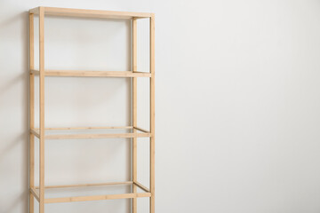 Stylish wooden shelf unit near light wall, closeup
