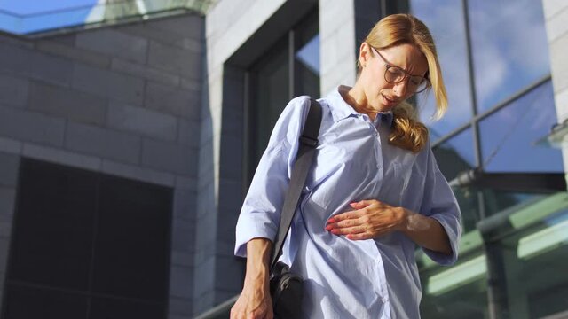 Worried woman in casual shirt touching her belly and frowning face, feeling acute abdominal pain, indigestion and nausea, heartburn, unhealthy eating, symptoms of pregnancy or periods