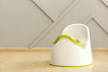 Potty on wooden floor near grey wall