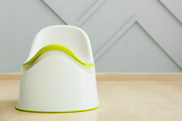 Modern potty on wooden floor near grey wall