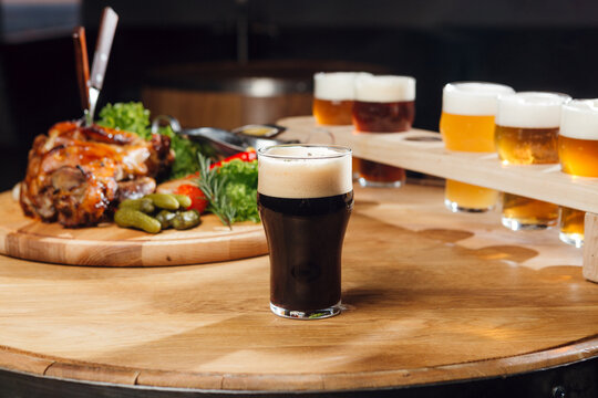 Black unfiltered craft beer at the table, with other beers and snaks at the background