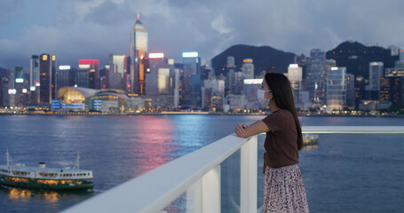 Fototapeta na wymiar Woman wear face mask and look at the city of Hong Kong