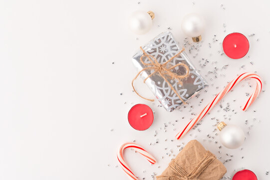 Festive composition on white background - presents, lollipops, candles, toys, silver confetti. - New Year, Christmas, birthday, family holidays and celebrations. The look of a high angle.