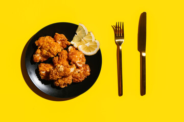 Plate with tasty popcorn chicken and lemon on color background