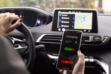 Woman sitting electric car charge using mobile application. Modern technology