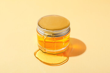 Jar of cosmetic product and honey on color background
