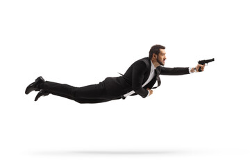 Full length profile shot of a man in a suit flying and holding a gun
