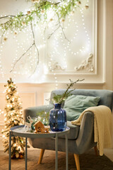 An armchair with pillows in a cozy room Classic apartments with decorated christmas tree and presents. Christmas evening in the light of candles and garlands.
