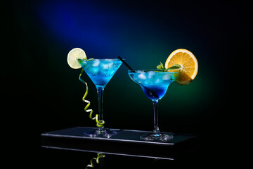 Glasses of Blue Lagoon cocktail on dark color background