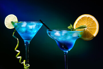 Glasses of Blue Lagoon cocktail on dark color background