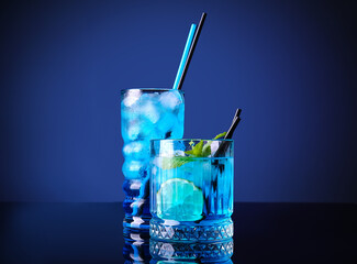 Glasses of Blue Lagoon cocktail on dark color background