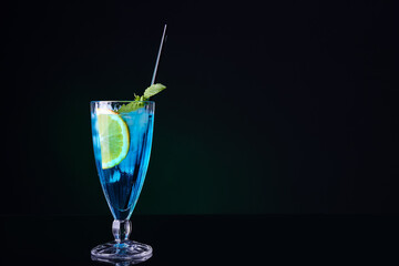 Glass of Blue Lagoon cocktail on dark background