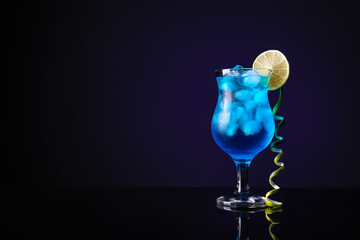 Glass of Blue Lagoon cocktail on dark background