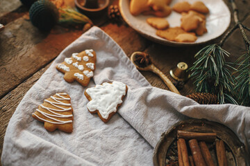 Fototapeta na wymiar Christmas tree gingerbread cookies on rustic table with napkin, decorations, spices. Atmospheric moody image. Making stylish christmas gingerbread cookies. Happy Holidays!
