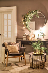 An armchair with pillows in a cozy room Classic apartments with decorated christmas tree and presents. Christmas evening in the light of candles and garlands. - 464329509