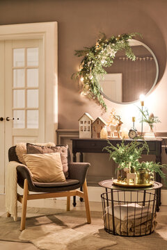 An armchair with pillows in a cozy room Classic apartments with decorated christmas tree and presents. Christmas evening in the light of candles and garlands.