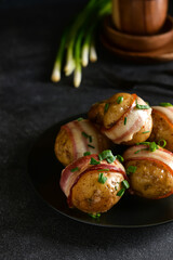 Plate of tasty baked potatoes with bacon on dark background