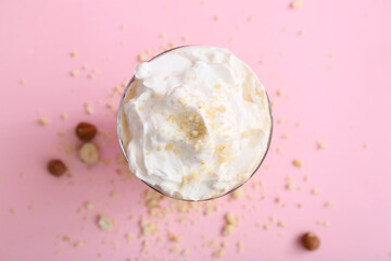 Glass of tasty latte with nuts on pink background
