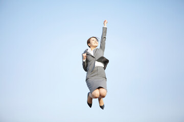 手を挙げ元気にジャンプするビジネスウーマン