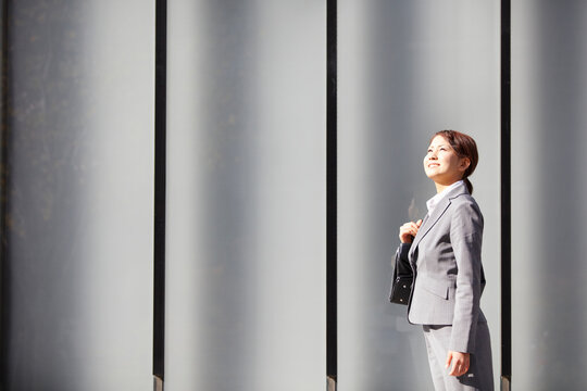 ビジネス街で上を見上げるフレッシュなビジネスウーマン