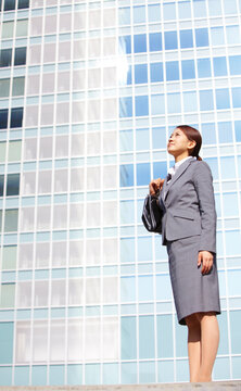 ビジネス街で上を見上げるフレッシュなビジネスウーマン