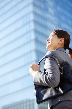 ビジネス街で上を見上げるフレッシュなビジネスウーマン