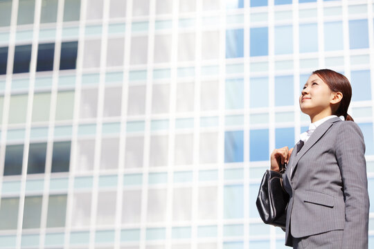 ビジネス街で上を見上げるフレッシュなビジネスウーマン