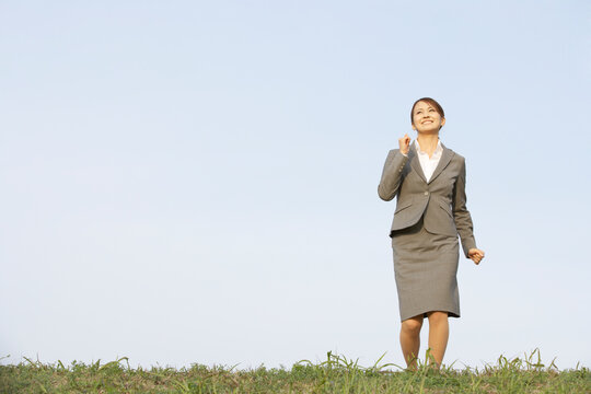 土手を元気に走るフレッシュなビジネスウーマン