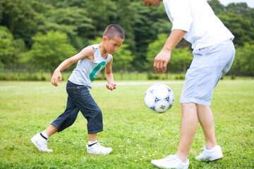 緑の芝生でサッカーをする元気な男の子と父親