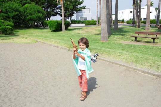 公園で遊ぶマントを着て鉄砲をもったハーフの男の子
