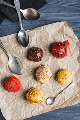 Parchment with balls of different tasty ice cream on black wooden background