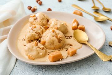 Plate of tasty caramel ice cream with nuts on white background