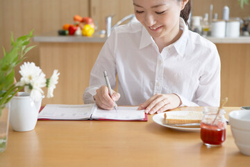 朝手帳にスケジュールを書く女性と朝ごはん