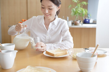 ミルクを注ぐ女性の朝食風景