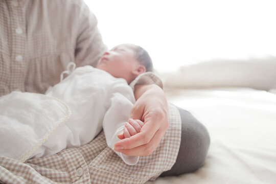 お母さんの腕に抱かれて眠っている男の子の赤ちゃん