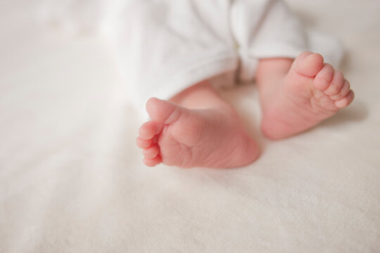 白い布団の上にある赤ちゃんの足
