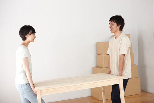引越しで机を運ぶ笑顔の女性と男性のカップル