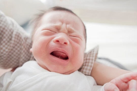 お母さんの腕に抱かれて泣いている男の子の赤ちゃん