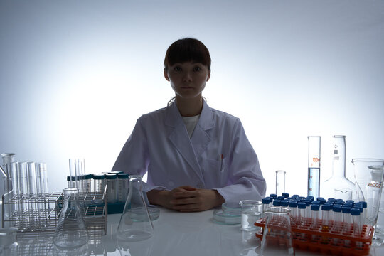 机の上にビーカーやフラスコや実験容器を並べている女性研究員