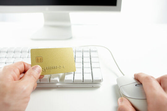 クレジットカードを持ってネットショッピングをしている男性の手