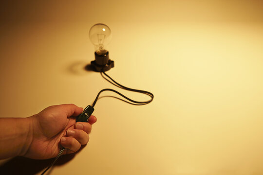 スイッチを切っている電球と手