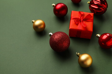 Different Christmas balls and gift box on green background, closeup