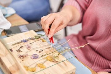 A woman lays out a composition. Master class on creating frame with Herbarium in tiffany technique...