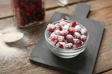 Bowl with tasty sugared cranberries on wooden background