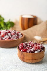 Bowls with tasty sugared cranberries on white background