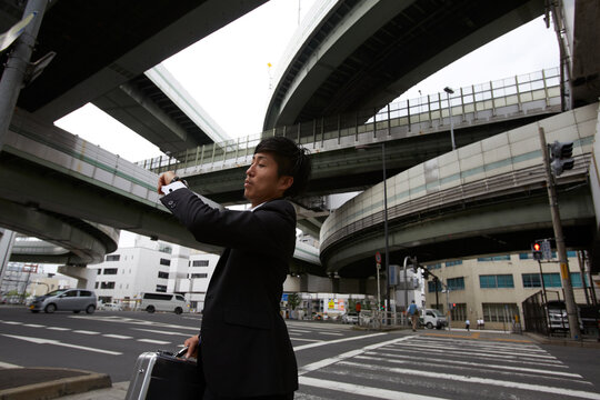 横断歩道の前で腕時計を見るビジネスマン